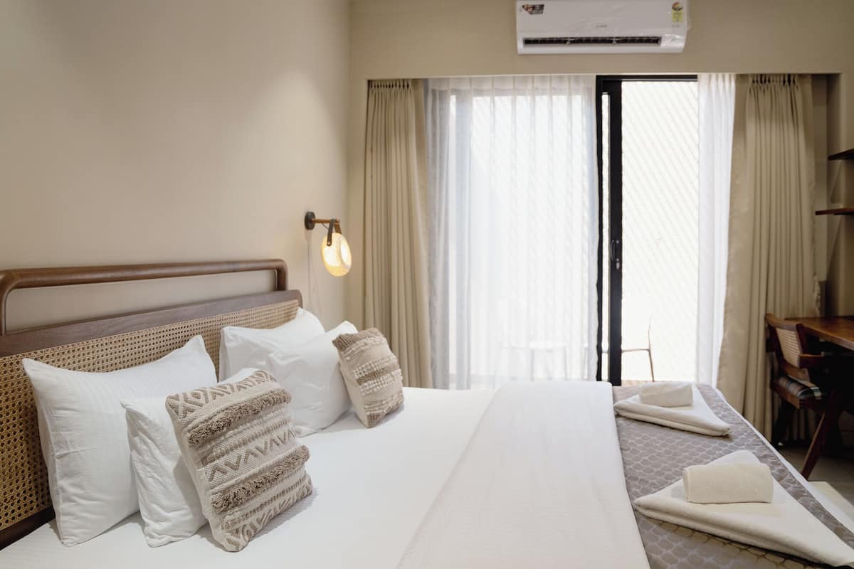 A hotel room with a large bed, a desk, and a window with curtains.