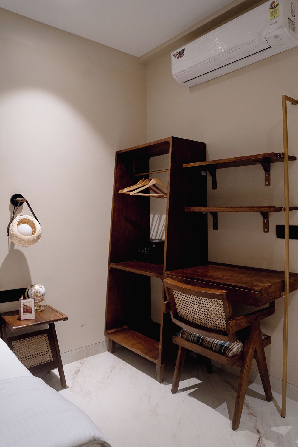 A compact bedroom with a wooden bunk bed, a small bedside table with a lamp, and a rattan chair.