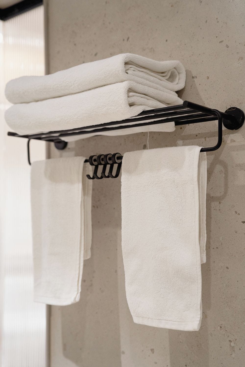 A towel rack with three folded white towels.