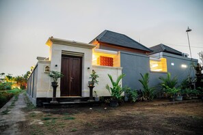 A modern house with a dark brown door, a small porch, and a garden with various plants. - Darta Ubud Rice Field Villas by EPS (Ubud)