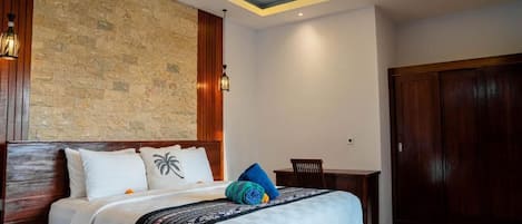 A modern hotel room with a stone accent wall, a wooden bed frame, and a desk with a chair.