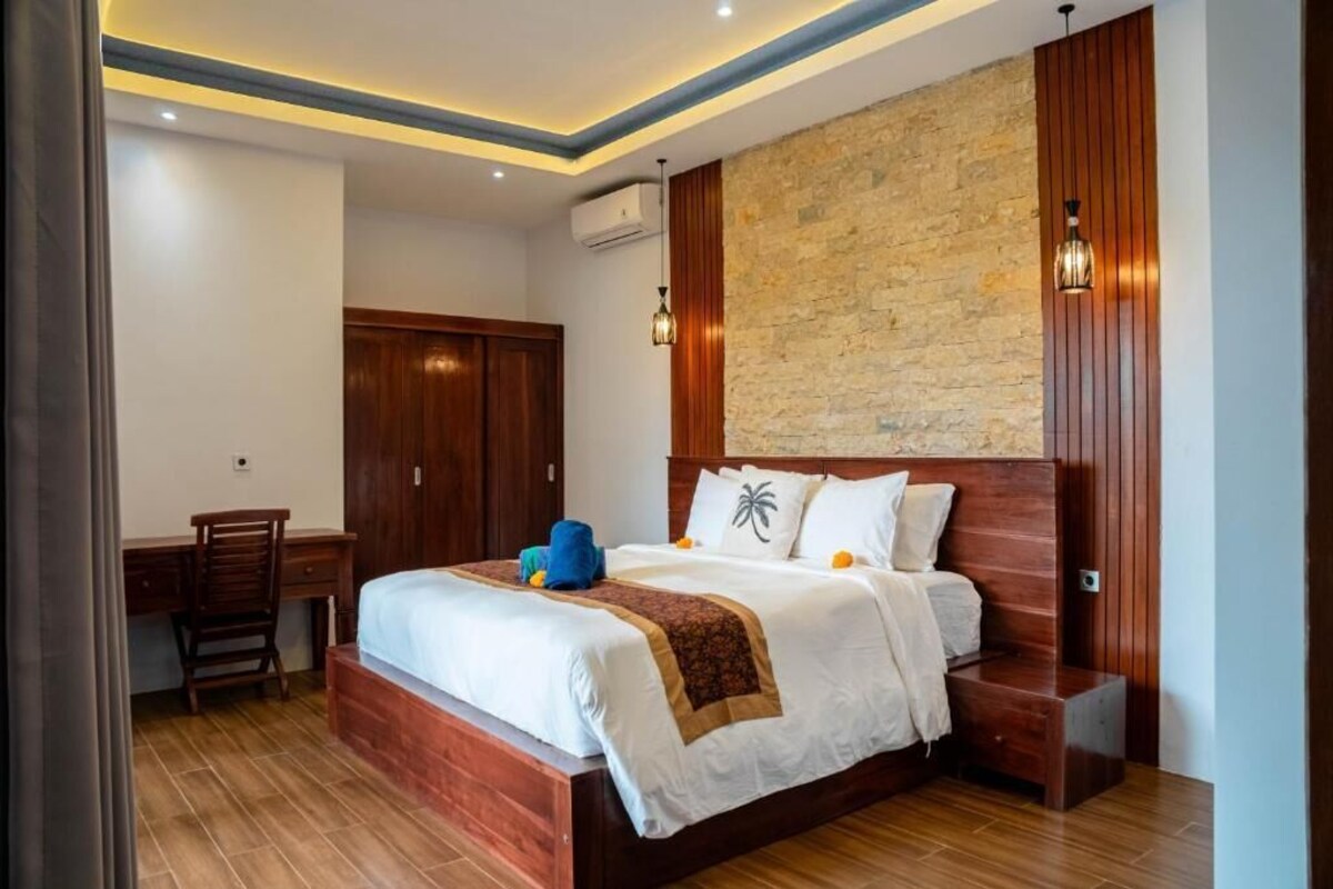 A bedroom with a wooden bed, a desk, and a chair.
