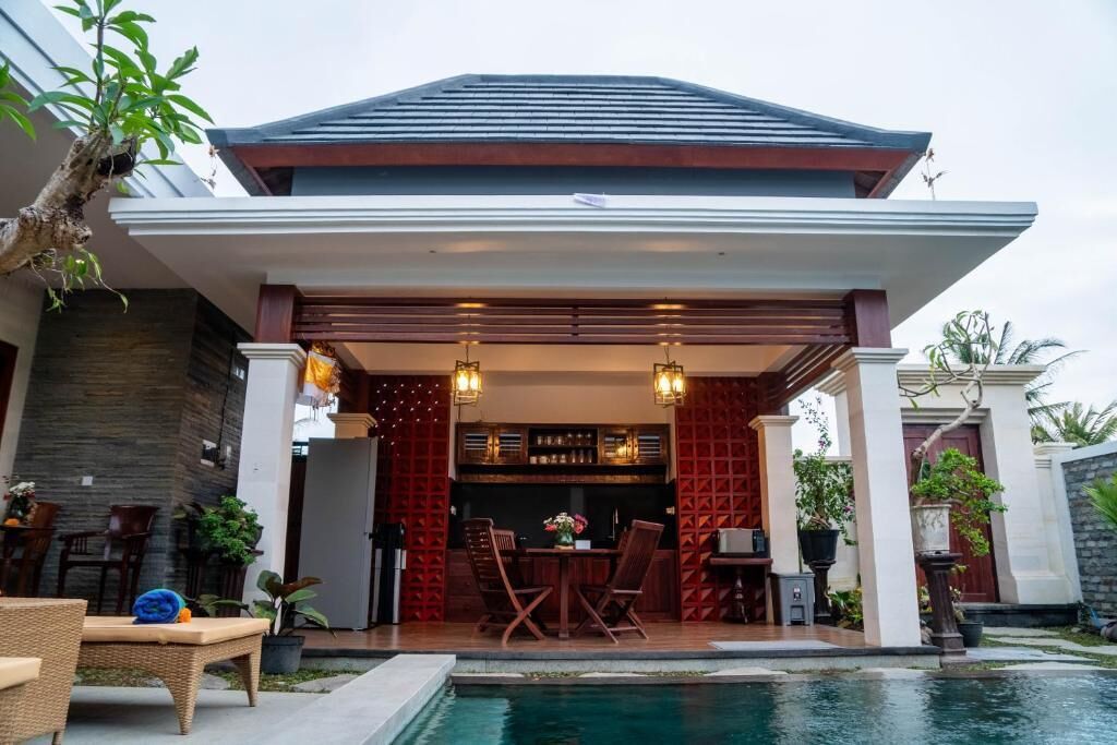 Un espacio al aire libre cubierto con piscina, muebles de madera y un bar.