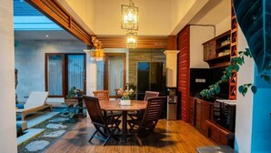 A modern kitchen with wooden cabinets, a dining area with a wooden table and chairs, and a staircase leading to an upper level. - Darta Ubud Rice Field Villas by EPS (Ubud)