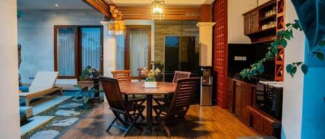 A modern kitchen with wooden cabinets, a dining area with a wooden table and chairs, and a staircase leading to an upper level.