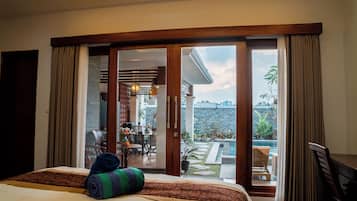 A hotel room with a bed, a view of the outdoor area including a pool and dining space.