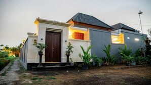 A modern house with a central entrance, a small porch, and a garden area with potted plants. - Darta Ubud Rice Field Villas by EPS (Ubud)