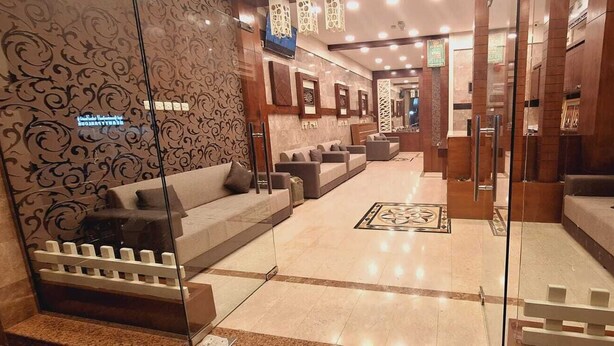 A hotel lobby with a reception desk, seating area, and decorative wall patterns. - STAR 4 SEASON (Salalah)
