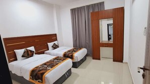 A hotel room with two beds, a wooden headboard, a mirror, and a door. - STAR 4 SEASON (Salalah)