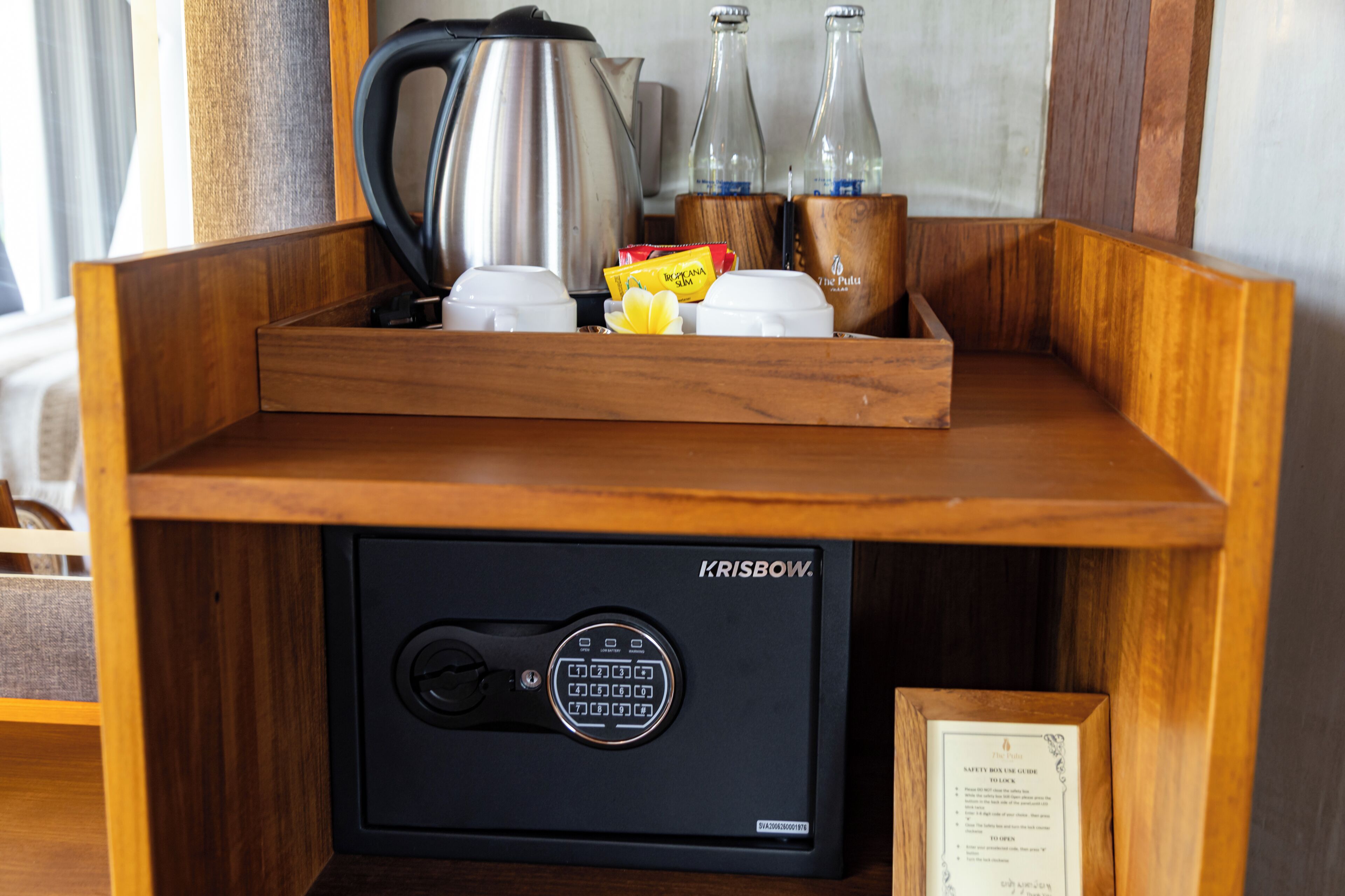 A wooden tray with a safe, a kettle, bottles, and some food items.
