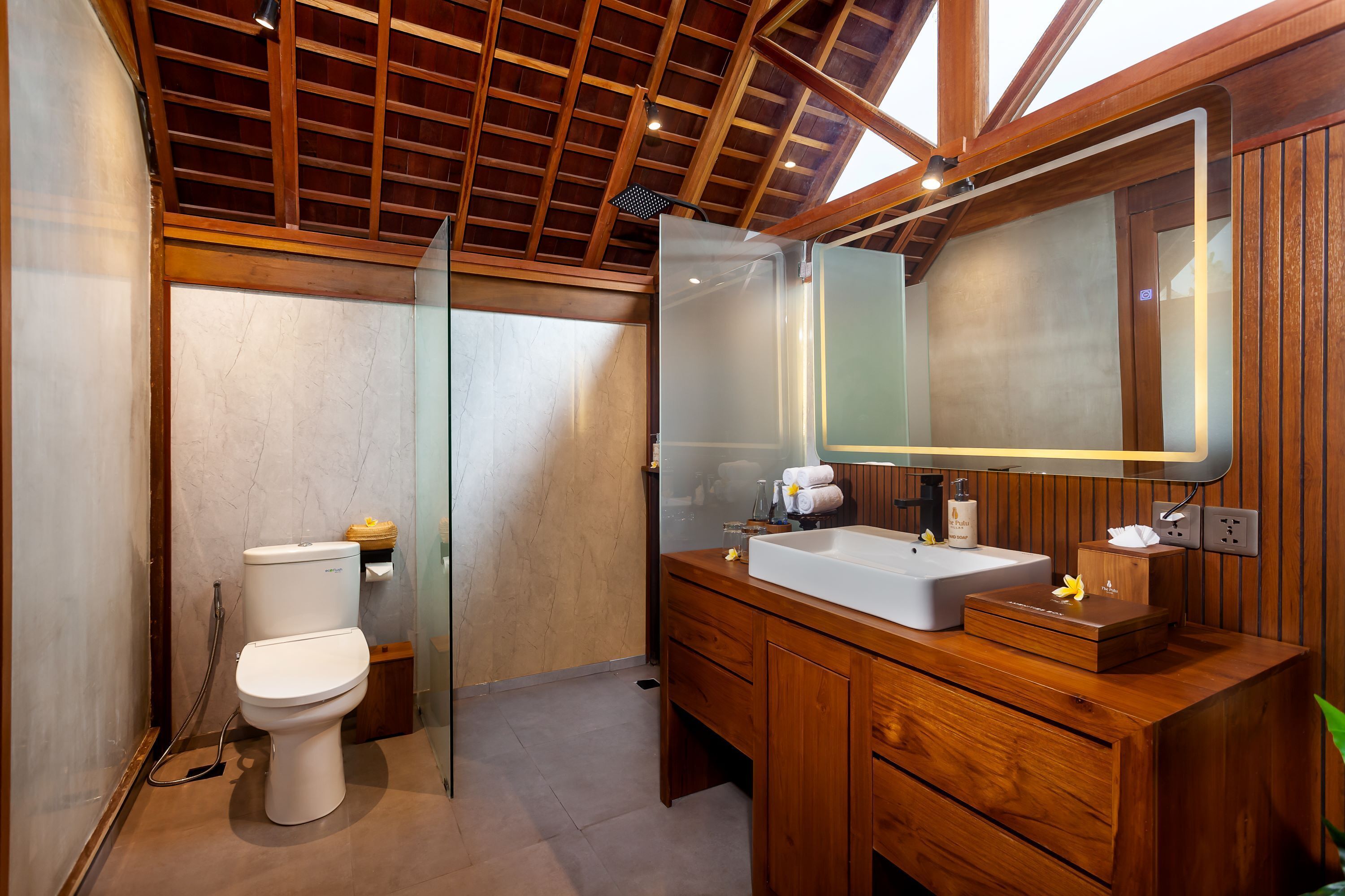 A bathroom with a wooden vanity, a large mirror, and a toilet.