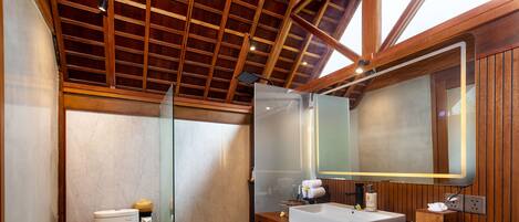 A bathroom with a wooden vanity, a large mirror, and a toilet.