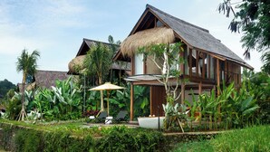 A bungalow with a thatched roof, a pool, and lush tropical vegetation. - The Pulu Villas by GenuineHost (Ubud)
