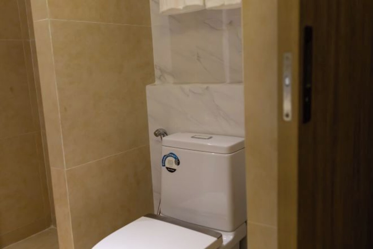 A bathroom with a toilet, a shower area, and a tiled floor.