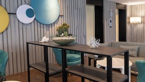 A modern living room with a dark wooden coffee table, teal armchairs, and a grey sofa. - Wyatt Hotel Jomtien Beach (Pattaya)