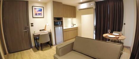 Un espacio habitable compacto con kitchenette, comedor y zona de estar.