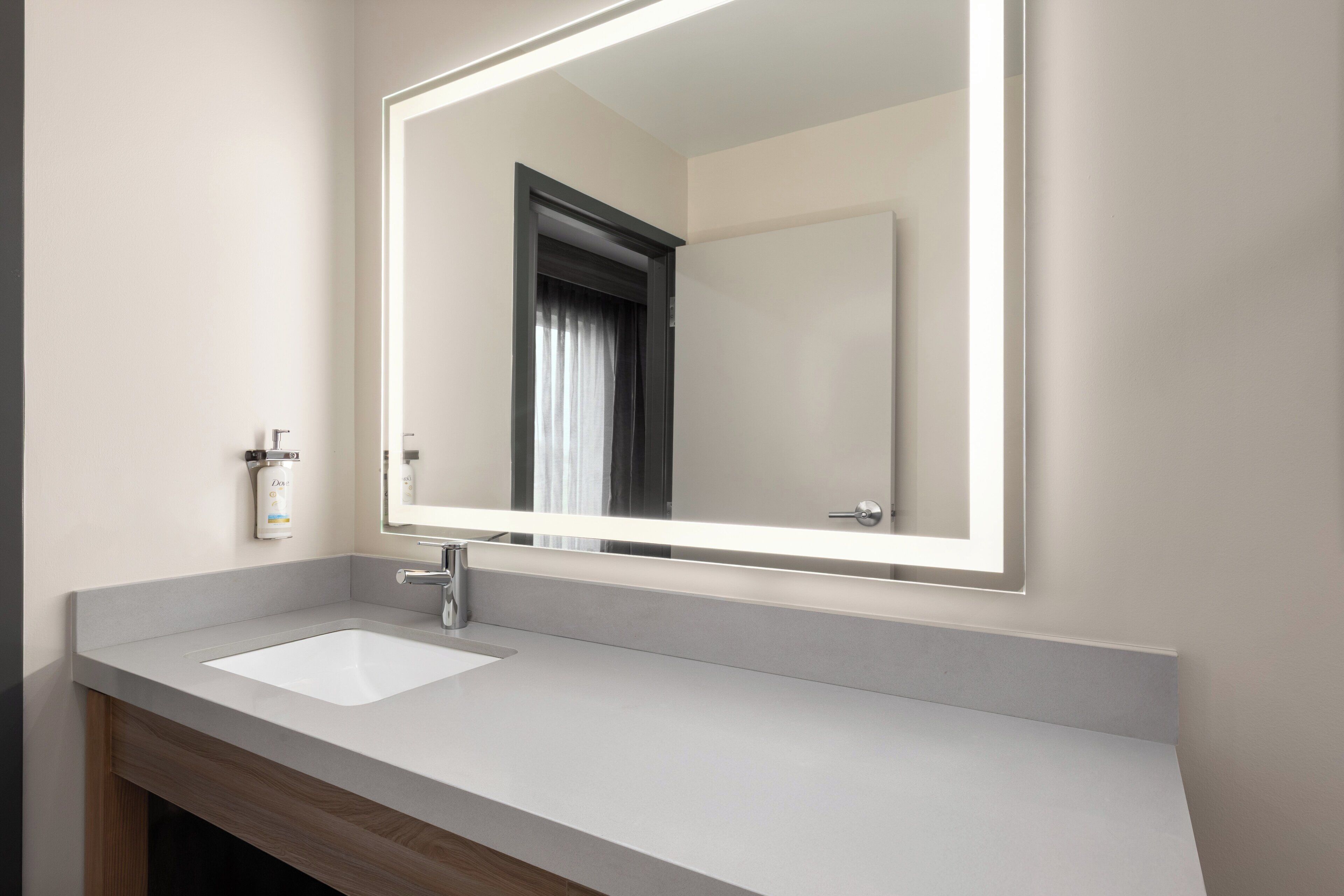 Une salle de bain moderne avec un lavabo blanc, un grand miroir et un meuble en bois en dessous.
