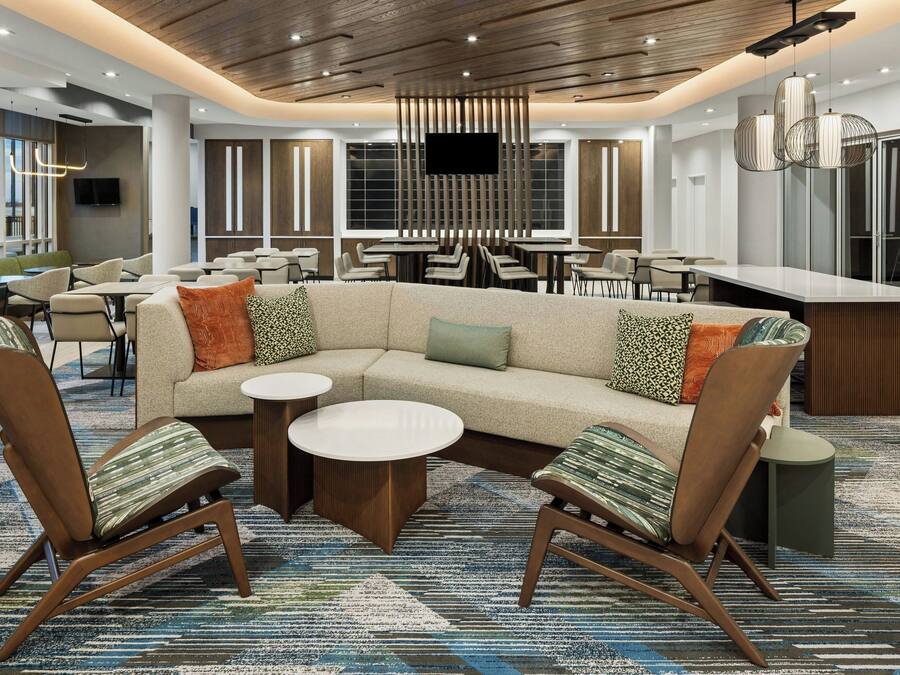 Un moderno vestíbulo de hotel con un sofá modular, mesas redondas y una zona de bar.