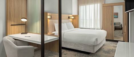 Una habitación de hotel con cama, escritorio, silla y armario.
