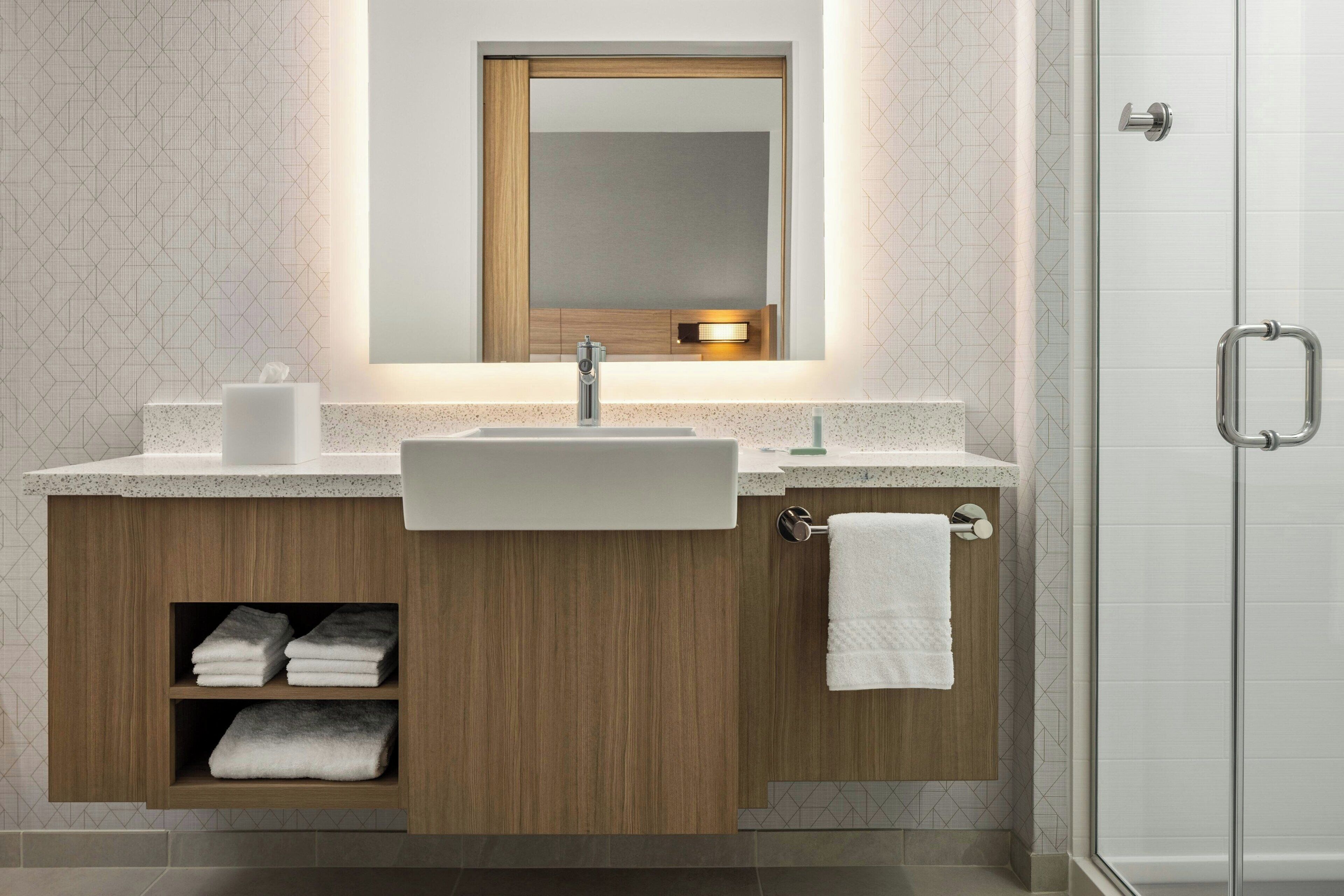 Un baño moderno con un lavamanos independiente, un espejo encima y una puerta de ducha de vidrio.
