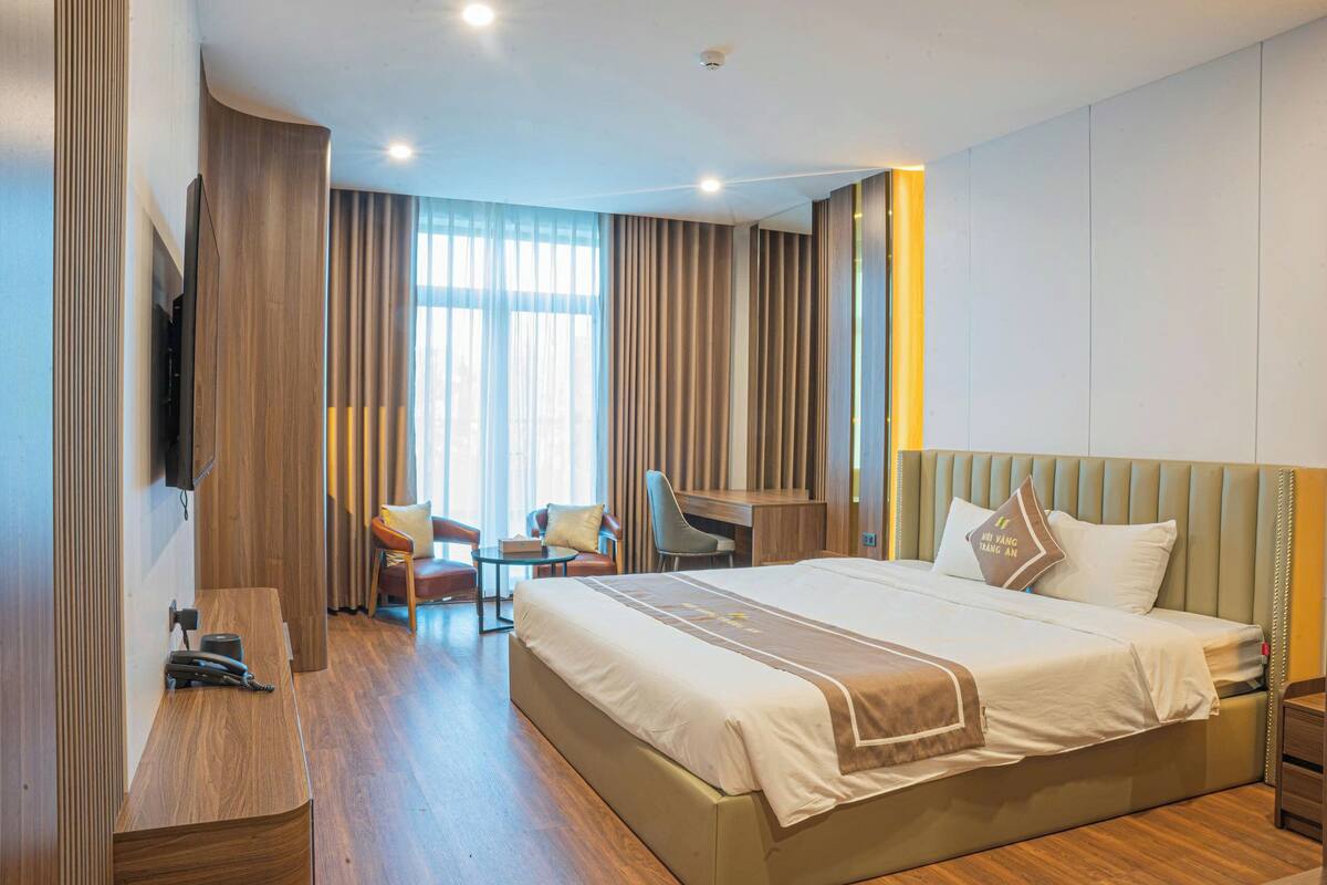 A modern hotel room with a large bed, a desk, and a chair.