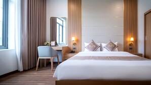 A hotel room with a large bed, a desk, a chair, and two bedside lamps. - Núi Vàng Tràng An (Hoa Lu)