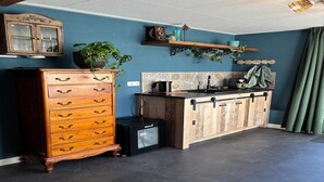 Eine kleine Küche mit einem Holzschrank, einem Kühlschrank und einer gefliesten Spritzwand.