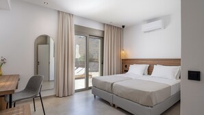 A modern hotel room with a bed, a chair, a table, and a sliding glass door to a balcony. - Imbros Villa 1 Free* Heated Pool & Tranquility! (Crete)