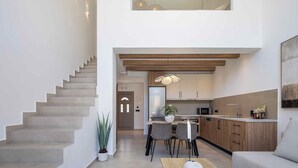 Un intérieur moderne comprenant un escalier, un coin repas et une cuisine.