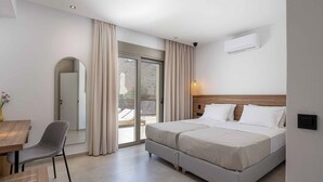 Une chambre d’hôtel équipée d’un lit, d’une chaise, d’une table, d’un miroir et d’une porte-fenêtre coulissante donnant sur l’extérieur.