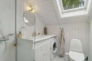A compact bathroom with a skylight, a washing machine, and a toilet.