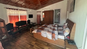 Une pièce avec un plafond en bois, un lit avec une literie à motifs, un bureau avec une chaise, une télévision et une armoire.