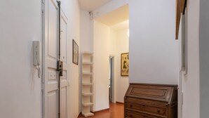 A hallway with white walls, a wooden dresser, and a white door with a phone. - GuestHost - Accommodation of 90 sqm on the first floor of a building with elevator, about 10 steps to access (NOT suitable for disabled), ideal for 4 guests.Located in a strategic position two passes from the Vatican and the Sala Nervi, just steps from S (Roma)