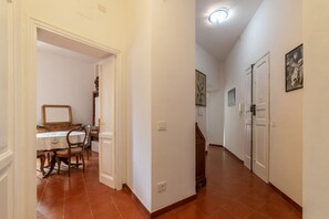 Un pasillo con comedor, paredes blancas y suelo de baldosas.