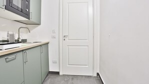Une cuisine équipée d’un four à micro-ondes, d’un évier et de meubles de rangement verts.