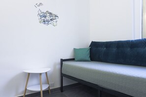 Een kleine kamer met een bed, een witte tafel en een muurstickers.