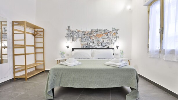 Une chambre à coucher avec un lit, une étagère en bois, une œuvre d’art murale et une fenêtre avec des rideaux.