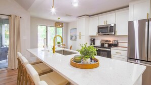 A modern kitchen with white cabinetry, stainless steel appliances, and a central island with seating. - Lagoon Views, Dog Friendly & Beautifully Renovated - Perfect for a Couple's Beach Getaway! (Kiawah Island)