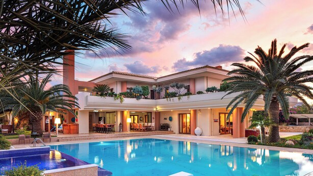Ein Hotel mit Pool, Sitzgelegenheiten im Freien und Blick auf den Sonnenuntergang.