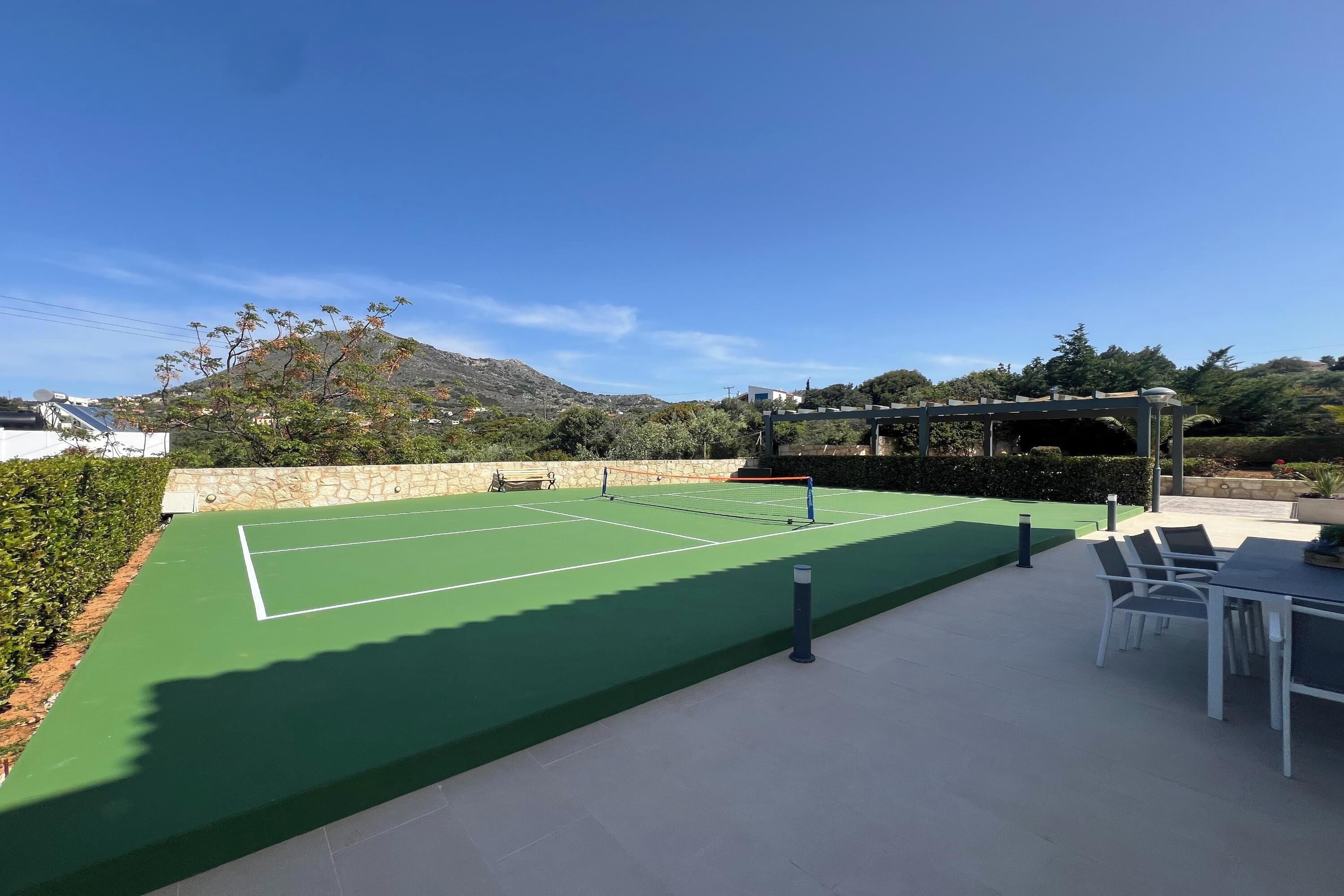Un court de tennis doté d’une zone pour les spectateurs et d’une pergola.