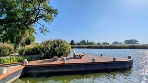 A wooden dock with a bench, surrounded by greenery and a calm body of water. - Charming Attic Retreat, Usedom (Usedom)