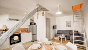 A modern kitchen with white cabinets, a wooden staircase, and a dining area with a table set for four. - Le Villandry beautiful apartment (Tours)