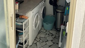 Una cocina compacta con lavadora, un mueble pequeño y suelo de baldosas.