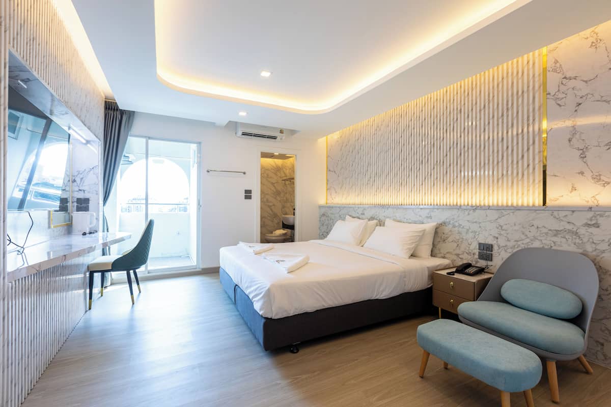 Habitación de hotel moderna con cama, mesita de noche, silla y vistas a la ciudad.