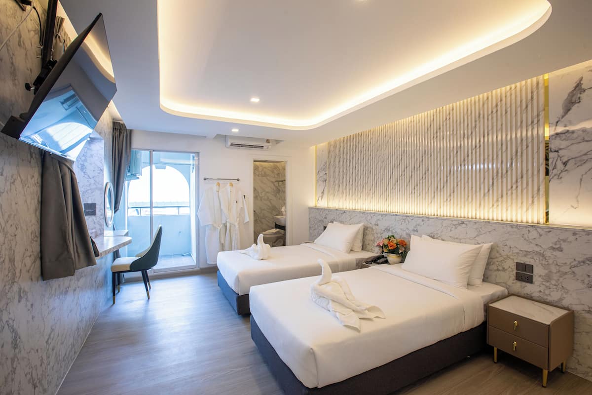 Una habitación de hotel moderna con dos camas, un escritorio y una zona de estar.