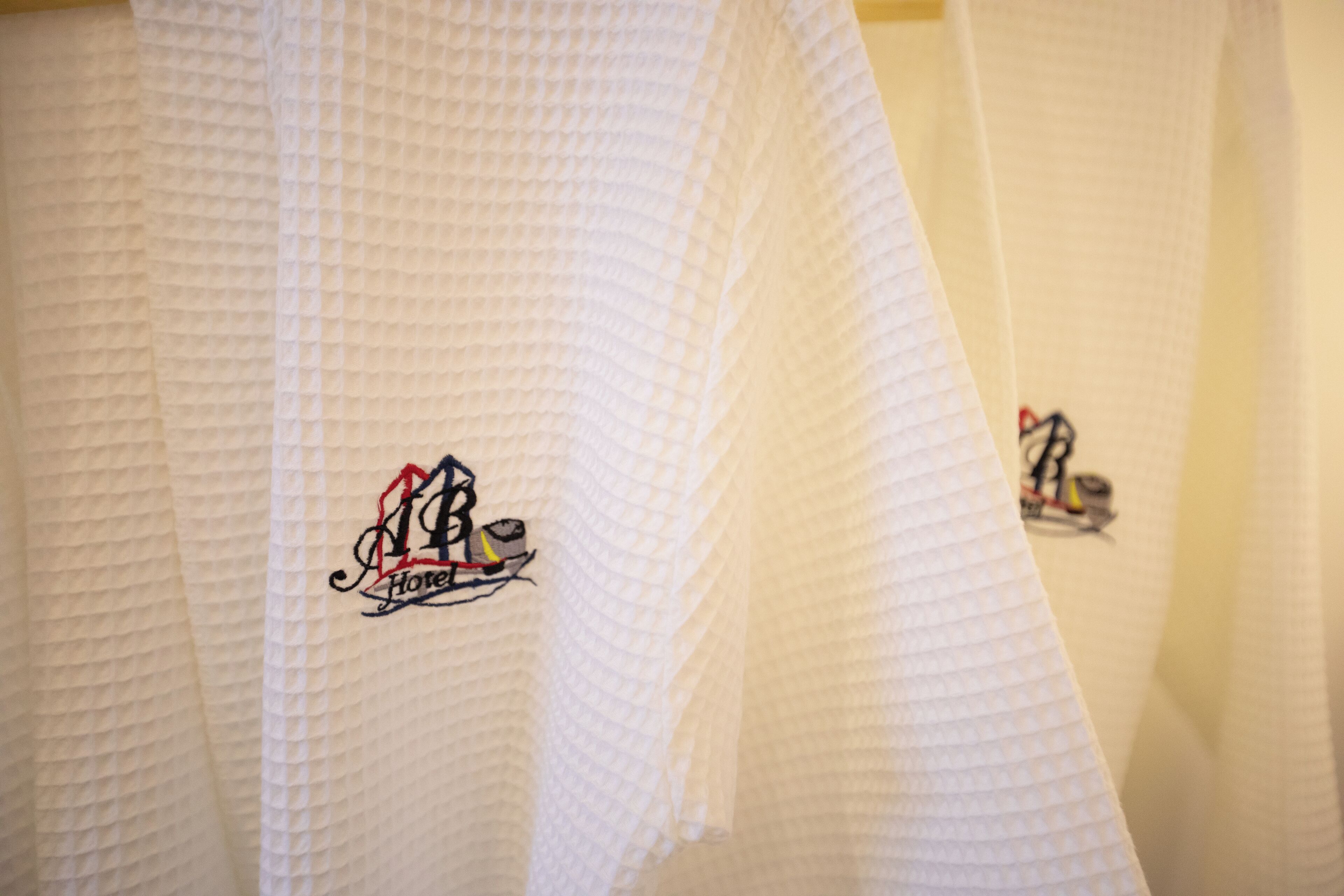 A close-up of a textured white curtain with a logo that includes a stylized 'M' and the word 'Hotel'.