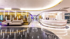 Un moderno vestíbulo de hotel con un mostrador de recepción curvo, una zona de estar elegante y un suelo de mármol brillante.