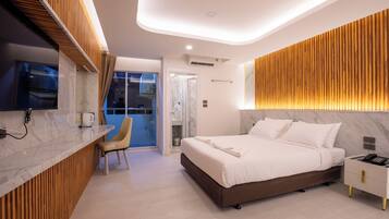 A modern hotel room with a marble bathroom, a wooden accent wall, and a bed with white linens.