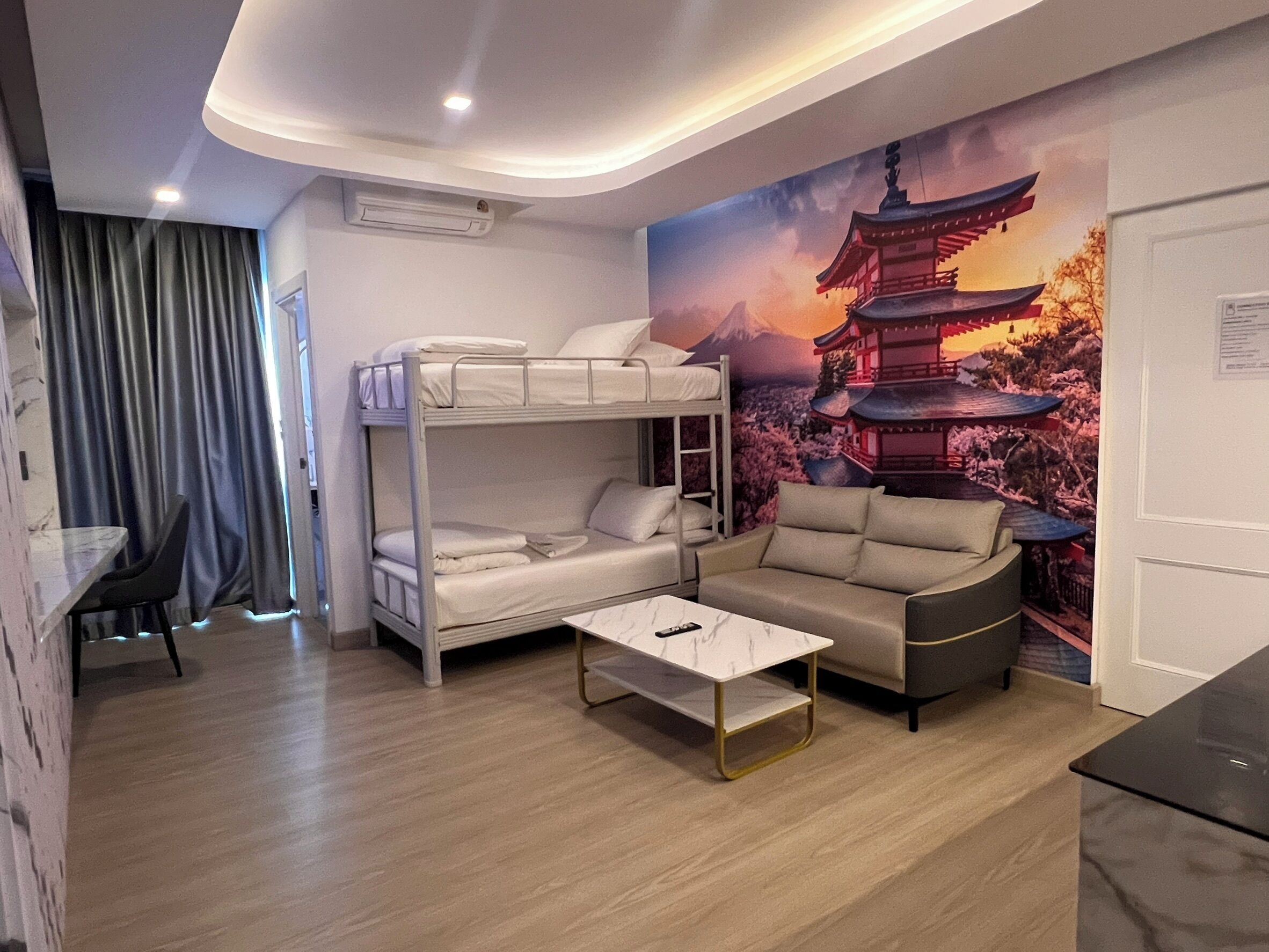 Una habitación con literas, un sofá, una mesa de centro y un mural de una pagoda.
