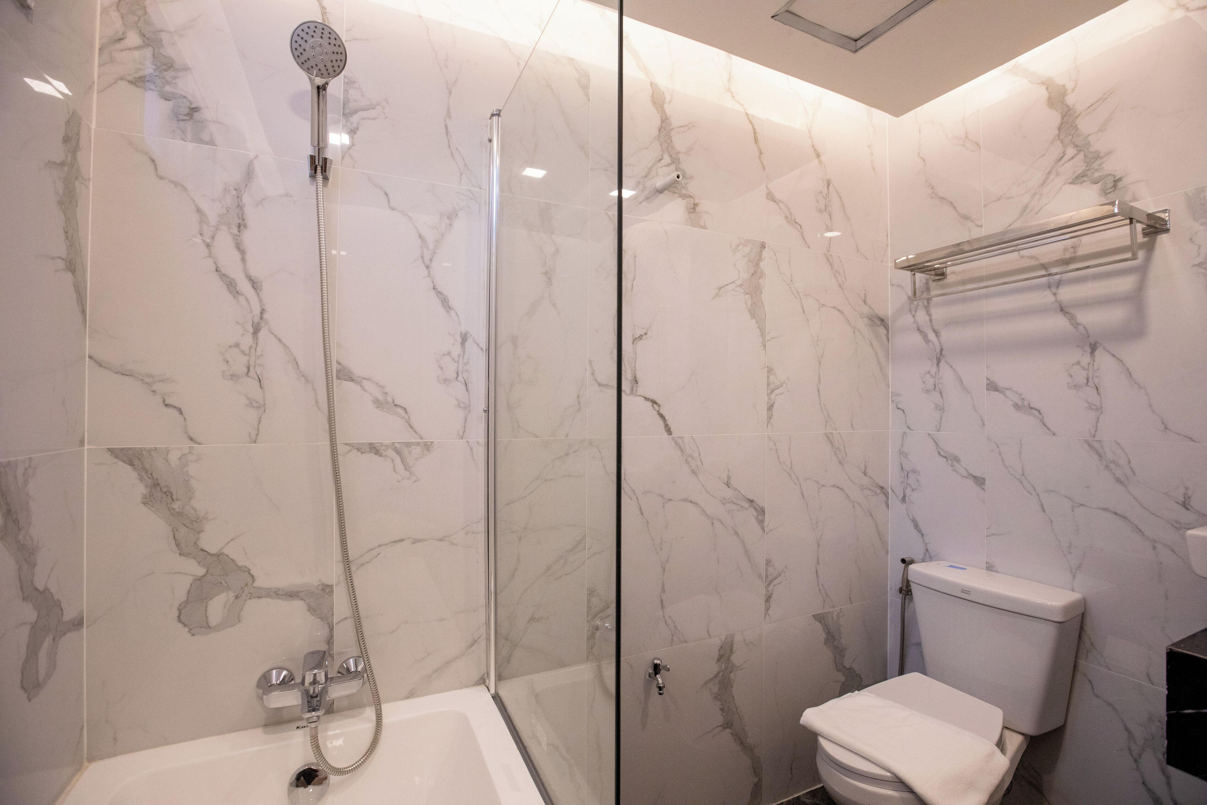 A modern bathroom with a glass-enclosed shower, a white bathtub, and a toilet.